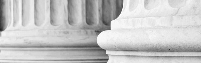 The image shows a row of classic stone columns with fluted shafts, representing architectural stability and strength.