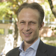 Arthur Van Benthem DSC Cropped A professional headshot of a person smiling in an outdoor setting with trees and a building in the background.