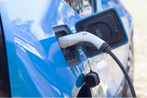 Blue EV Plug A blue electric vehicle is being charged with a white charging cable plugged into its charging port.