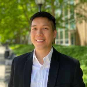 Man in suit smiling in front of trees