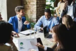 Stock image of professionals sitting around a table looking at charts and laptops