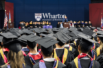 Photo of Wharton undergraduate graduation showing a group of graduates from behind wearing their regalia and facing the stage
