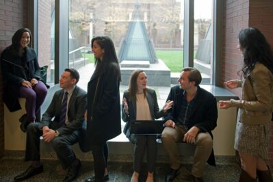 Wharton students sitting and standing around a window as they talk