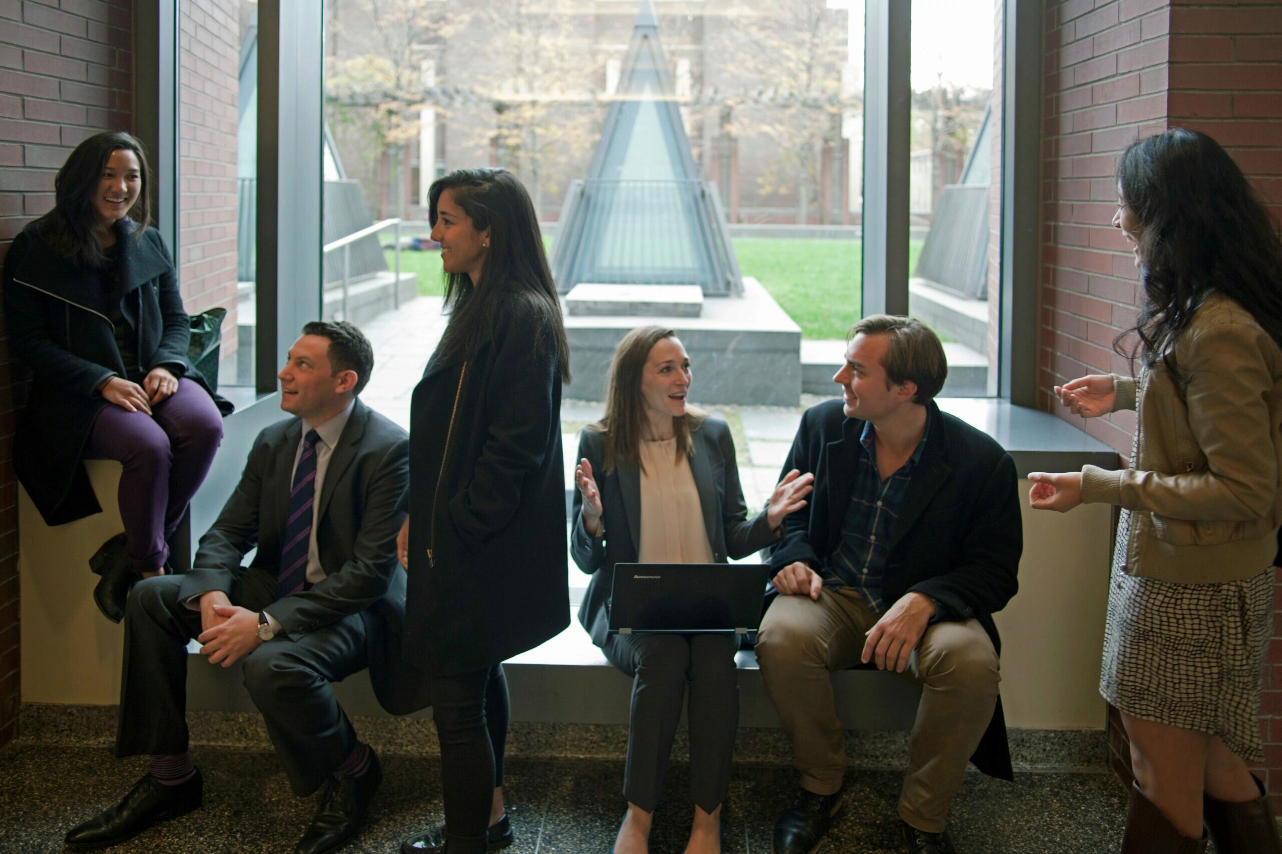 Wharton students sitting and standing around a window as they talk