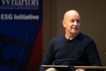 Bobby Turner smiling in a navy blue sweater in front of a pop-up banner that reads Wharton ESG Initiative.