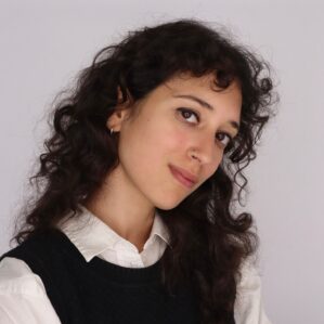 Juliet Gelfman Randazzo smiling in a white button down and black sweatervest against a white backdrop