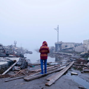 Flooding in Argentina Child standing on wood looking out at flooded area, surrounded by debris