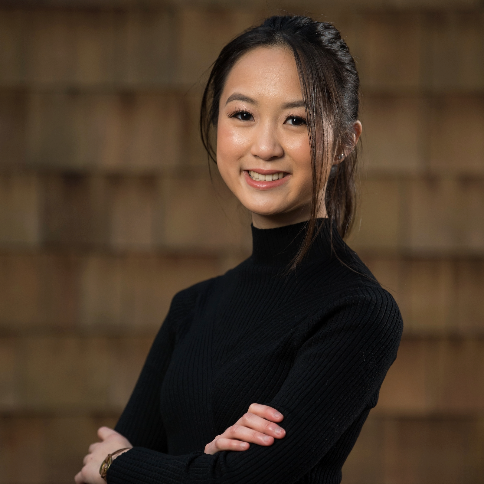 Marielle Kang Headshot Marielle Kang posing for a professional headshot in a black turtleneck against a brick wall