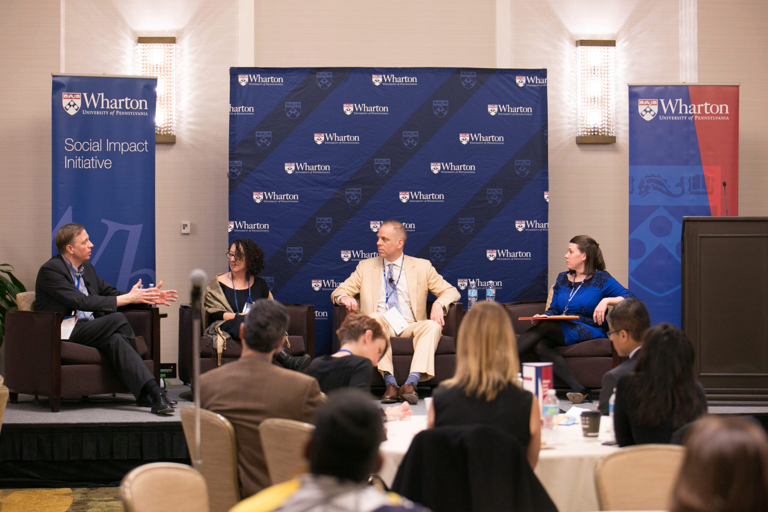 Suzanne Biegel 1 Image from 2017 Social Impact Initiative event with Suzanne Biegel, Sandra M. Hunt, and others on stage speaking before a room of professionals.