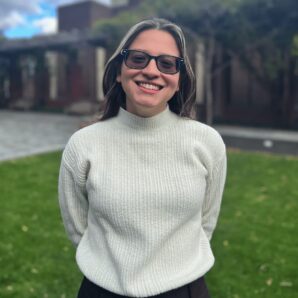 Teodora Dragic smiling posed in a cream sweater outside on the Penn campus standing in a grassy area