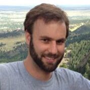 Brian B Headshot of a person with a beard, smiling outdoors with a mountainous landscape in the background.