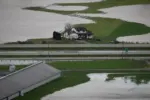 A house sits on high ground among flooded farmland.