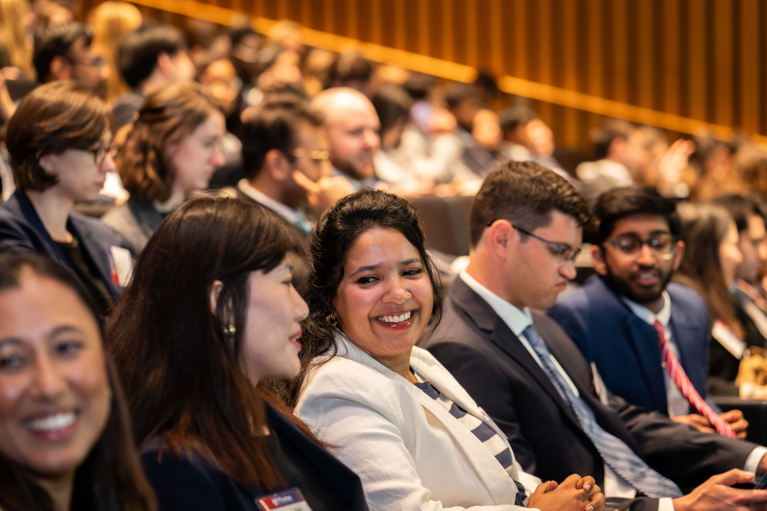 Close up shot of students smiling and talking in a full lecture hall.