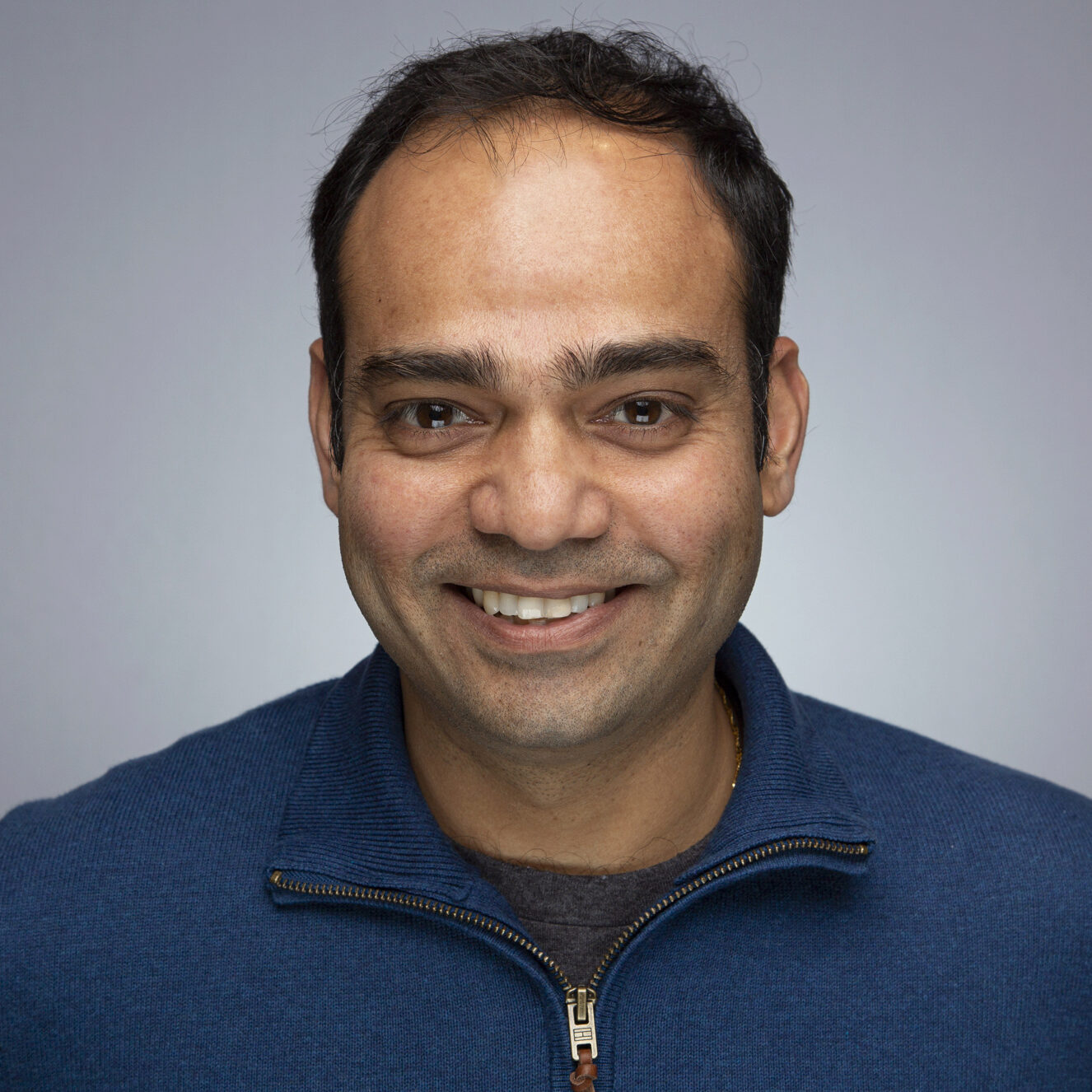 Ashwin Malshe Ashwin Malshe smiles in a blue quarter zip in front of a light grey background.