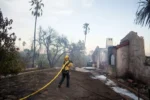 A firefighter prepares to spray a home during the Edgehill Fire on August 5 in San Bernardino, California.