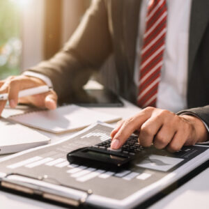 Businessman,Or,Accountant,Working,On,Laptop,Computer,With,Business,Document, Stock image of person in a suit using a calculator and taking notes