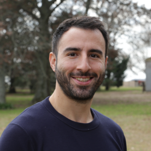 Ignacio Marchionna smiles in a navy blue shirt in front of foliage.