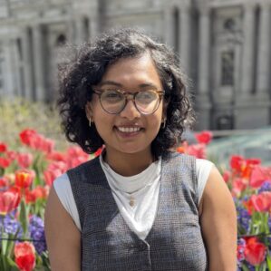 Rishika Ghosh poses smiling in front of pink tulips.