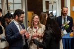 A group of people talk in a circle holding drinks and smiling.