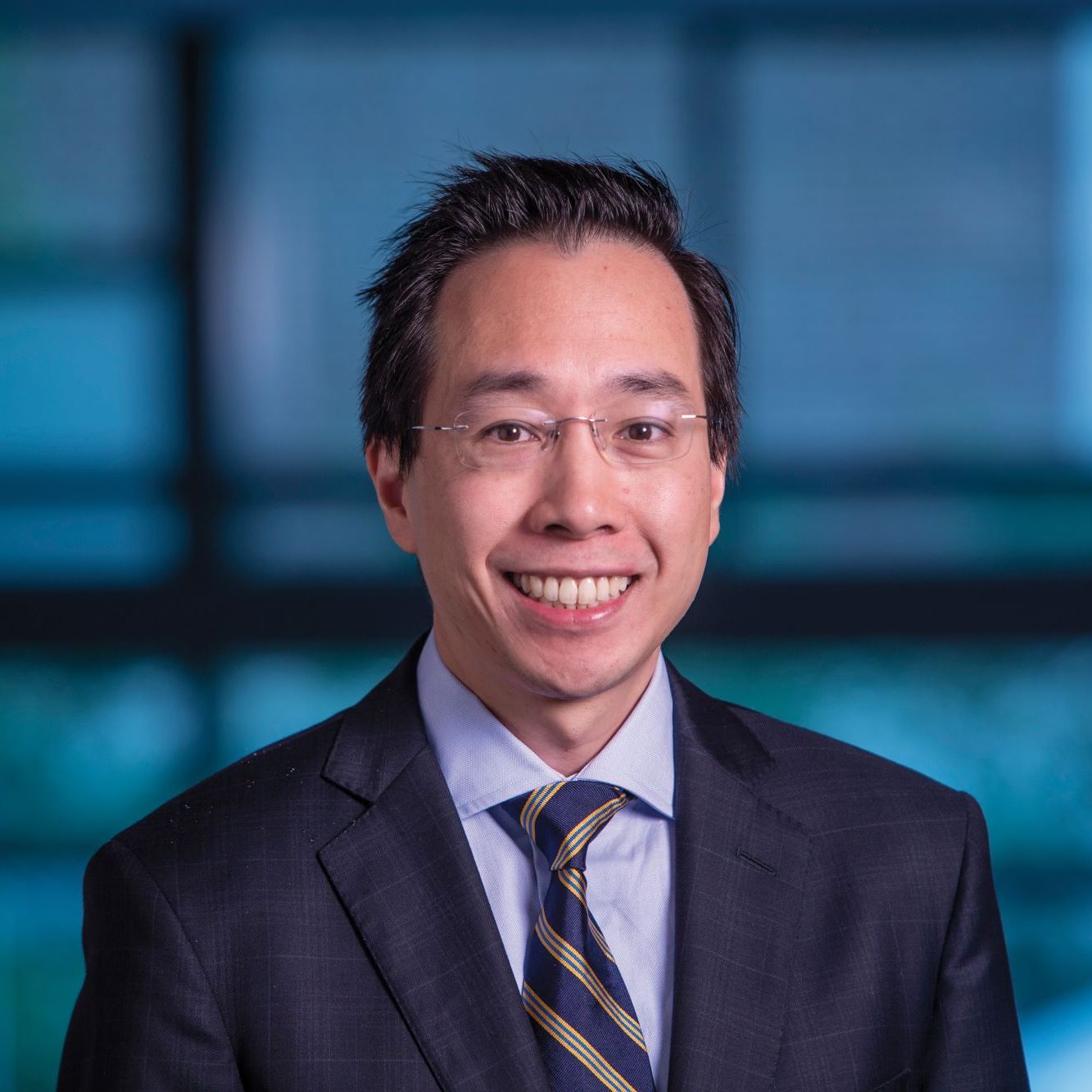Benjamin Lee smiles for a professional headshot in a suit and tie.