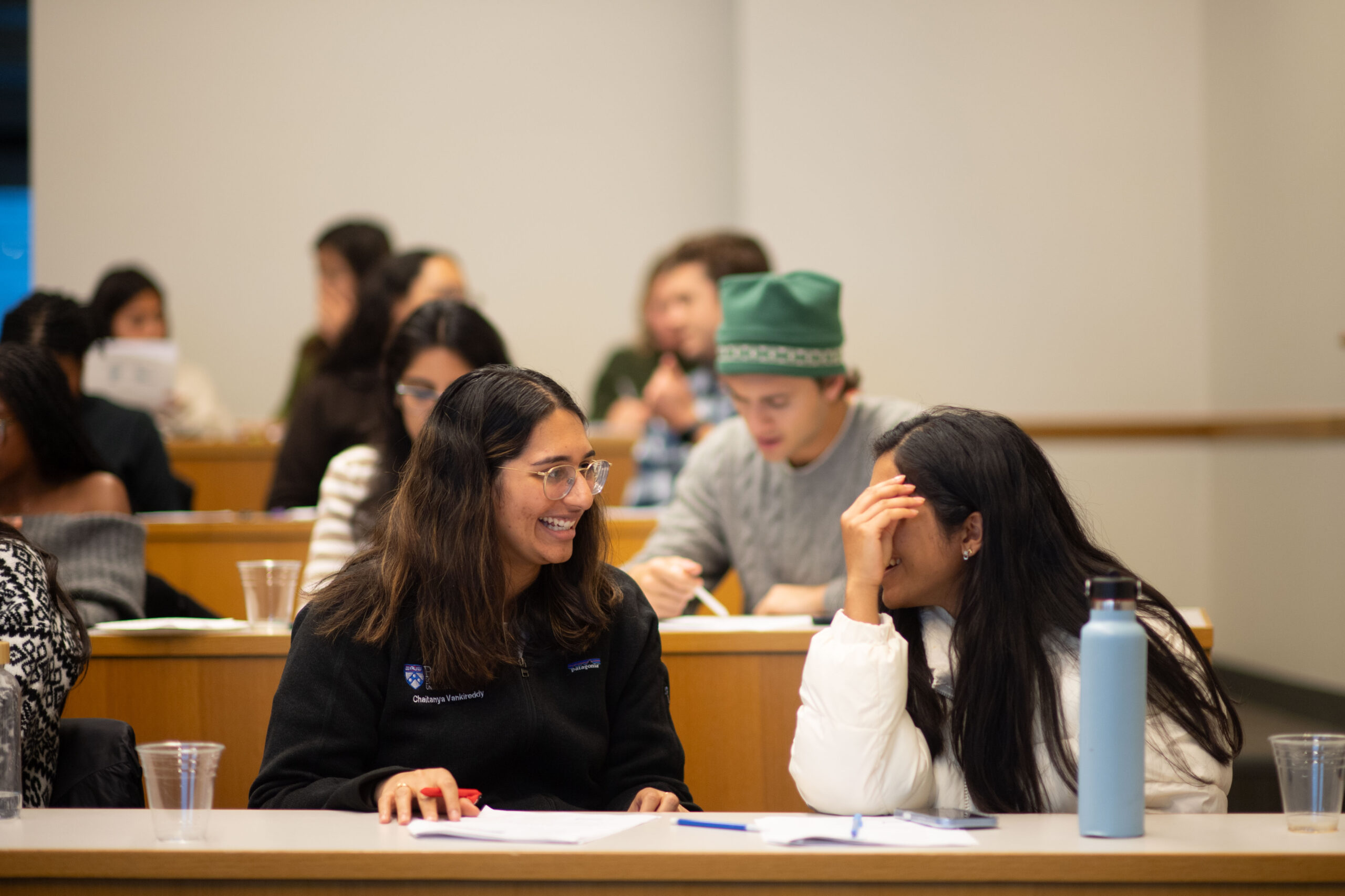 Close up photo of two students talking and smiling in a classroom